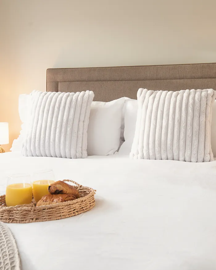 Bedroom with a large bed, striped cushions and warm bedside lamps