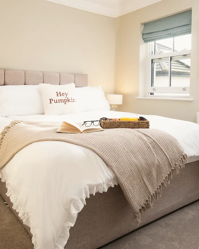 Bedroom with a Hey Pumpkin cushion and an open book on the bed
