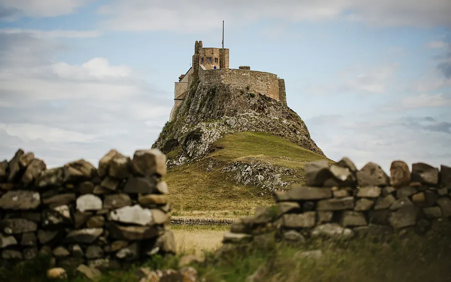 Lindisfarne Castle on its rock, seen over a dry-stone wall on Holy Island